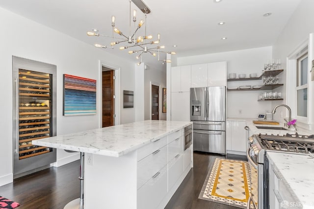 kitchen featuring appliances with stainless steel finishes, white cabinets, a kitchen island, dark hardwood / wood-style floors, and sink