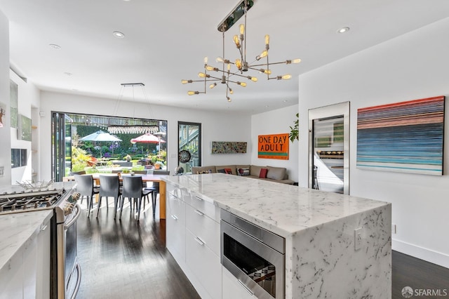 kitchen featuring white cabinets, hanging light fixtures, a kitchen island, dark wood-type flooring, and stainless steel appliances