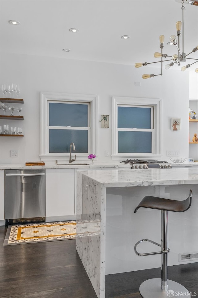 kitchen featuring light stone counters, a breakfast bar area, appliances with stainless steel finishes, and dark wood-type flooring