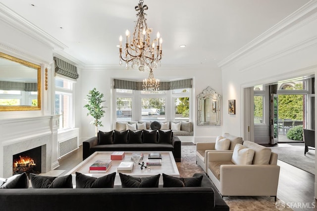 living room featuring a fireplace, wood finished floors, ornamental molding, and an inviting chandelier