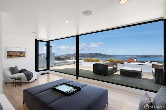living room with a wall of windows, wood finished floors, recessed lighting, and a water view