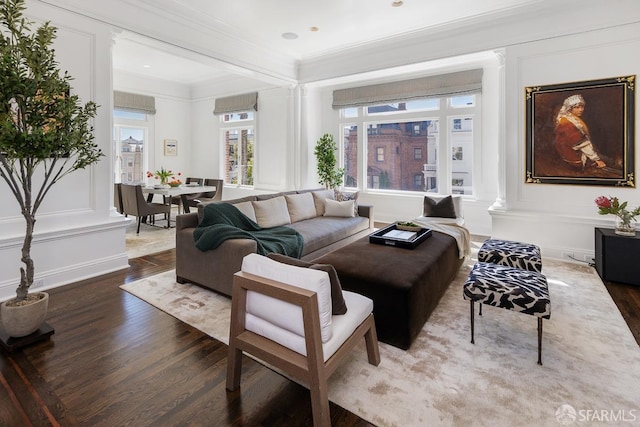 living room featuring wood finished floors, ornamental molding, and decorative columns