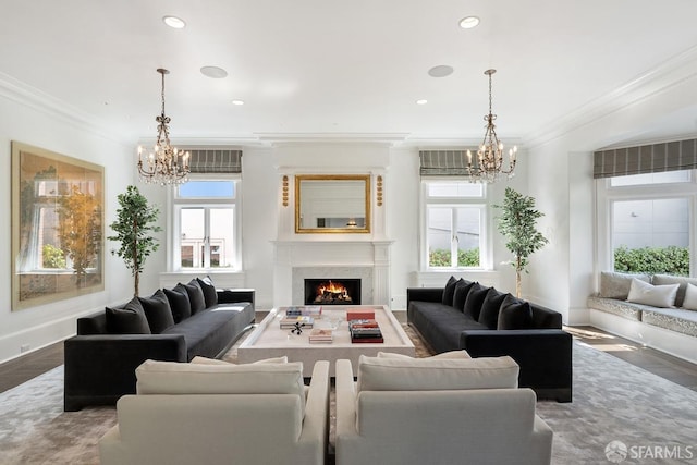 living area featuring ornamental molding, a lit fireplace, and a notable chandelier