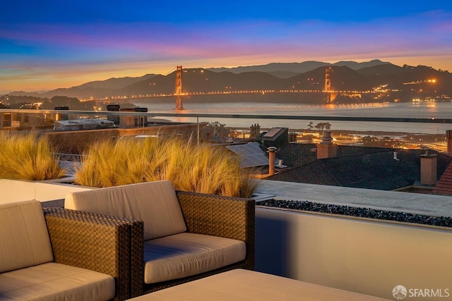 patio terrace at dusk with a water and mountain view and a balcony