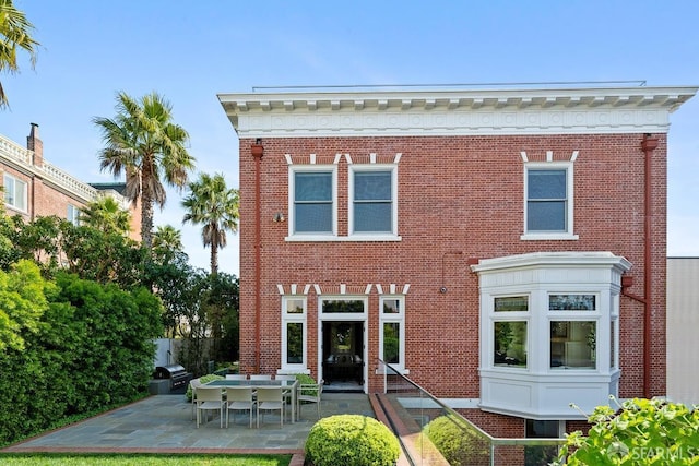 back of house featuring brick siding and a patio