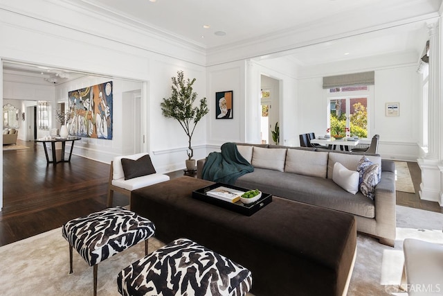 living area with wood finished floors, a decorative wall, and crown molding