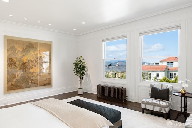 bedroom with radiator heating unit, baseboards, wood finished floors, and ornamental molding