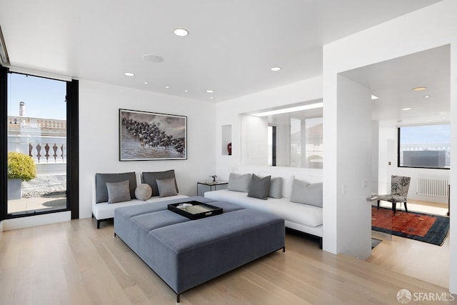 living room featuring recessed lighting, radiator heating unit, and light wood-type flooring