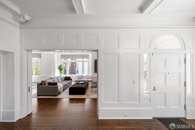 entrance foyer with a decorative wall, dark wood-style floors, and ornamental molding
