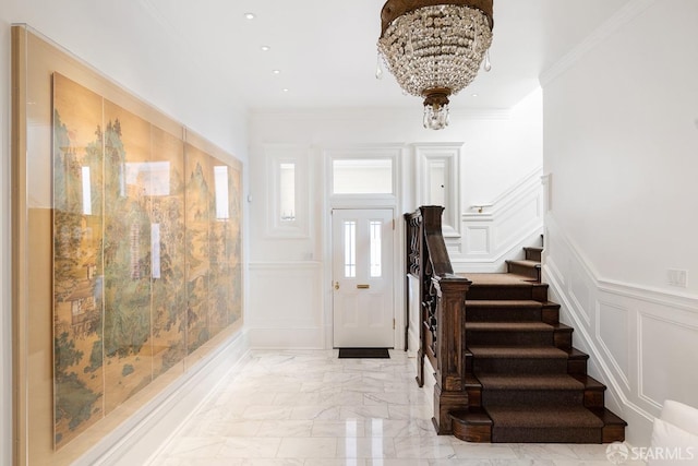 entrance foyer with a decorative wall, stairs, marble finish floor, a wainscoted wall, and ornamental molding