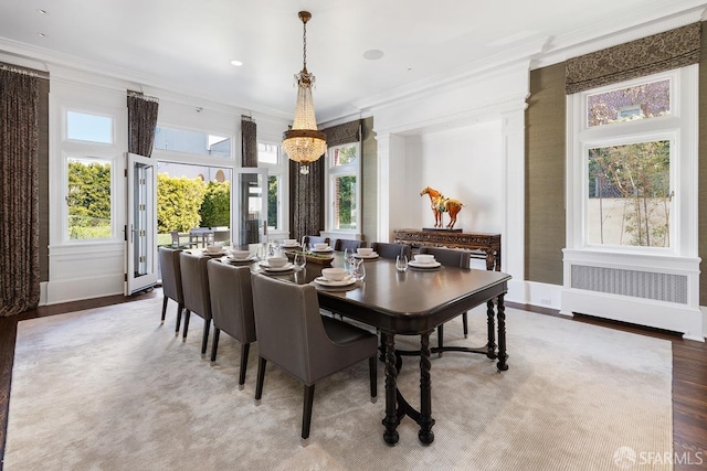 dining room featuring crown molding, wood finished floors, a chandelier, radiator, and baseboards