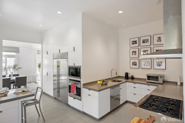 kitchen featuring a sink, light tile patterned floors, built in appliances, a toaster, and white cabinets