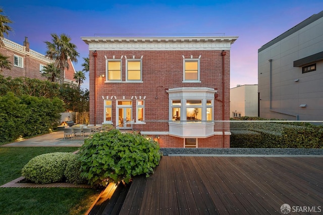 back of house featuring french doors, brick siding, and a patio