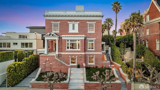 view of front facade with a chimney and brick siding