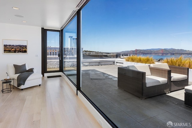 interior space featuring a wall of windows, wood finished floors, a water view, and access to outside
