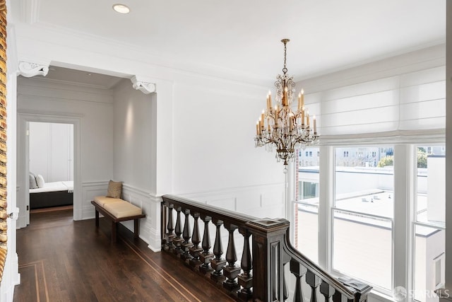 corridor with recessed lighting, an inviting chandelier, a decorative wall, dark wood-type flooring, and ornamental molding