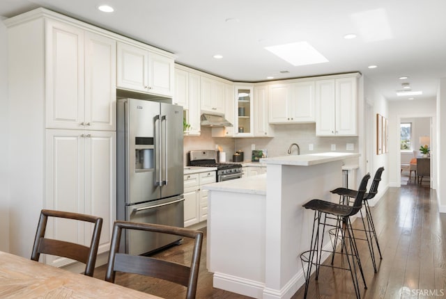 104 Bache St Unit A, San Francisco, CA 94110 - kitchen with appliances with stainless steel finishes, under cabinet range hood, a breakfast bar, dark wood-style floors, and backsplash