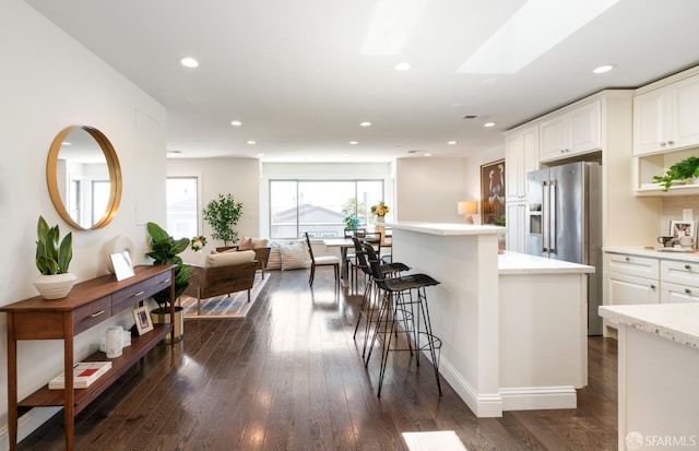 104 Bache St Unit A, San Francisco, CA 94110 - kitchen featuring stainless steel fridge, dark wood finished floors, white cabinetry, a center island, and a breakfast bar area