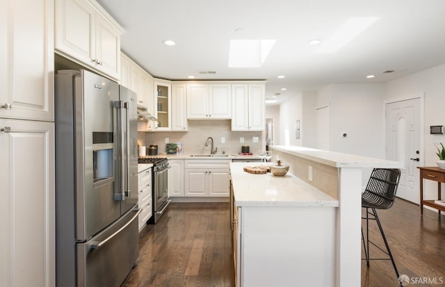 104 Bache St Unit A, San Francisco, CA 94110 - kitchen featuring stainless steel appliances, a kitchen island, a sink, a kitchen breakfast bar, and a skylight