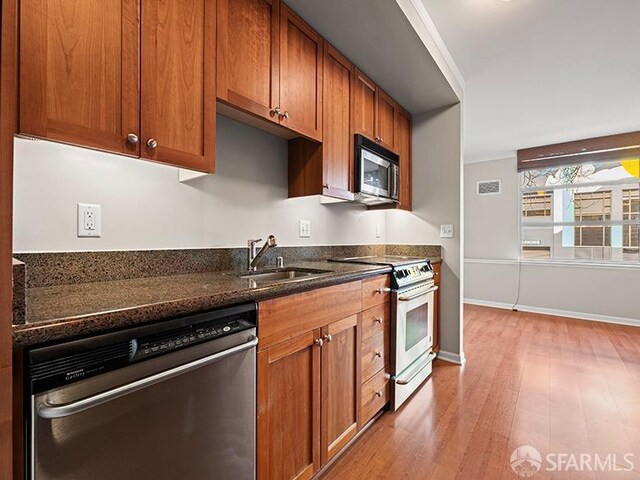 1701 Jackson St Unit 105, San Francisco, CA 94109 - kitchen with a sink, light wood-type flooring, appliances with stainless steel finishes, and brown cabinets