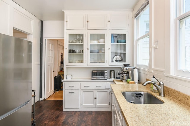 kitchen with white cabinets, stainless steel fridge, sink, dark hardwood / wood-style floors, and light stone countertops