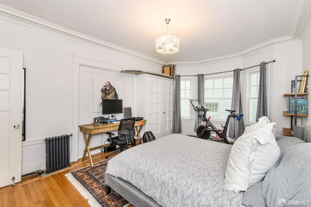 bedroom with ornamental molding, radiator, wood-type flooring, and a notable chandelier