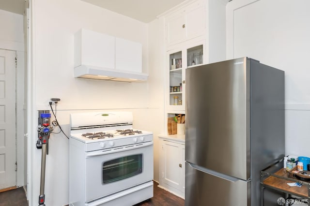 kitchen featuring stainless steel fridge, dark wood-type flooring, white cabinets, white range with gas stovetop, and extractor fan