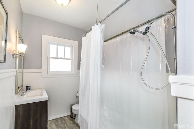 bathroom with wood-type flooring, walk in shower, vanity, and toilet