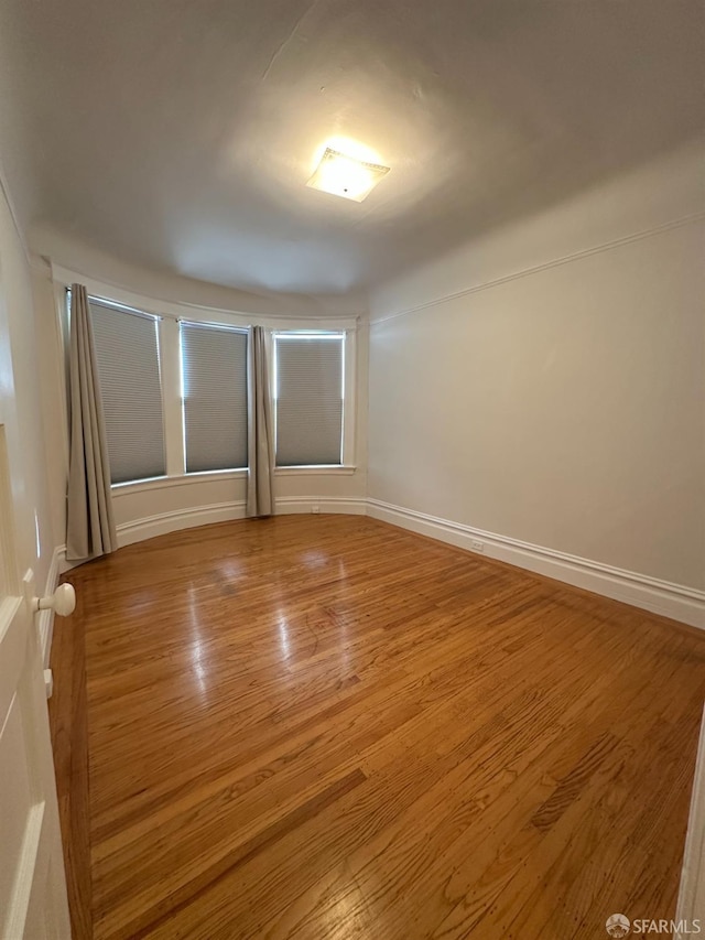 unfurnished room featuring baseboards and wood finished floors