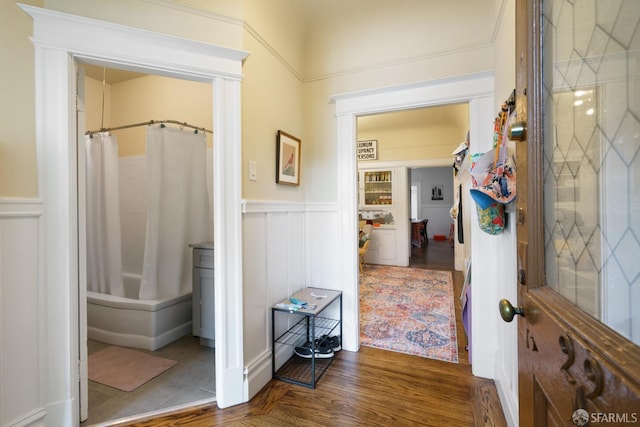 corridor featuring a wainscoted wall, a decorative wall, and wood finished floors