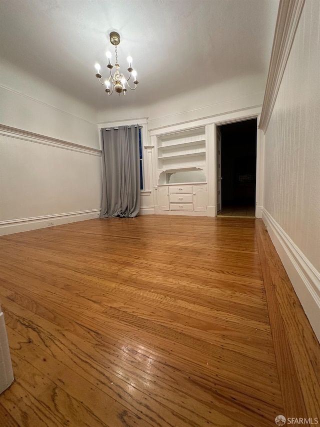 interior space featuring baseboards, a chandelier, and wood finished floors