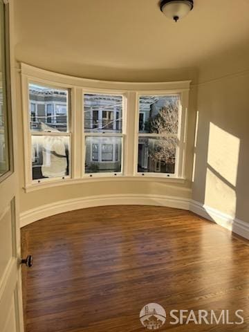 unfurnished room with dark wood finished floors and baseboards