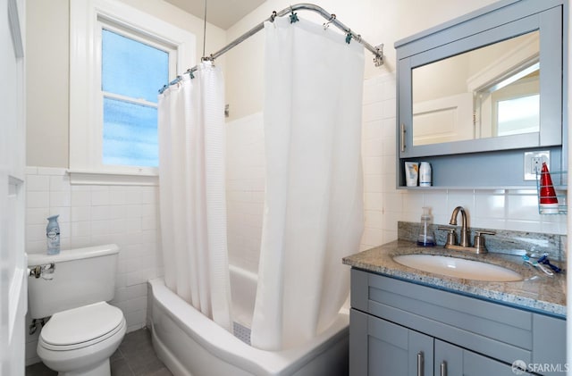 full bath featuring toilet, shower / tub combo with curtain, tile walls, and vanity