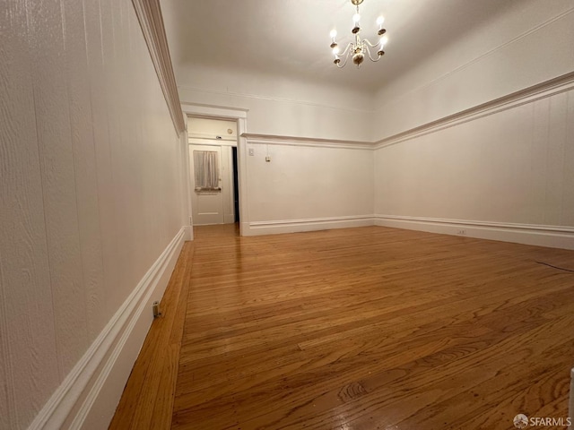 unfurnished room with a chandelier and wood finished floors