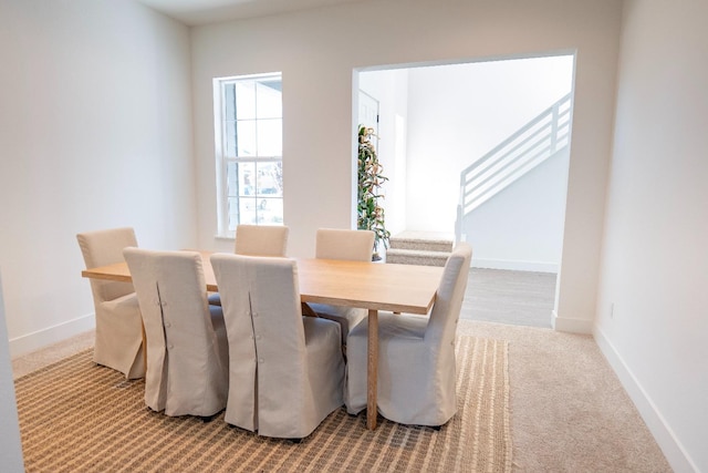 carpeted dining space featuring stairs and baseboards