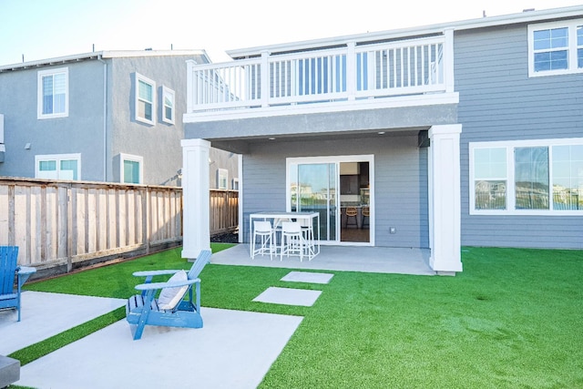 back of house featuring a fenced backyard, a lawn, a patio area, and a balcony