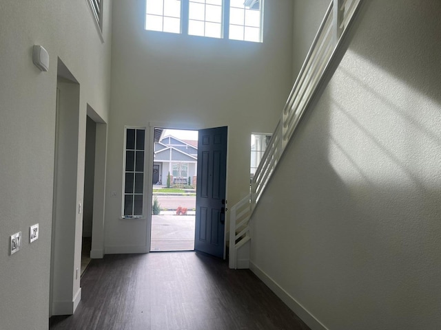 entryway with dark wood-type flooring and a towering ceiling