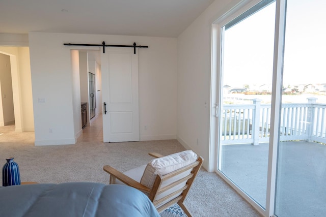 sitting room with baseboards, light carpet, a barn door, and a wealth of natural light