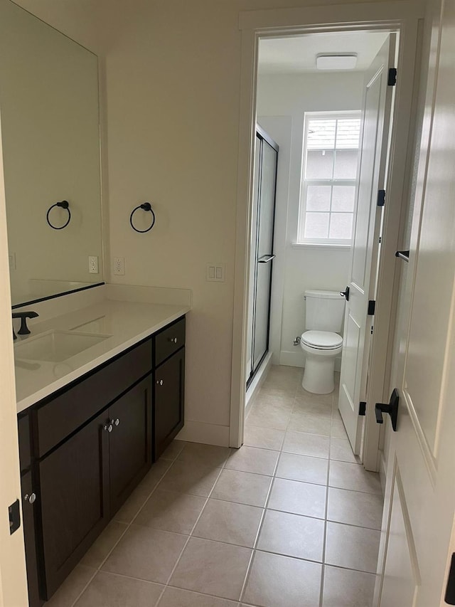 bathroom with toilet, vanity, tile patterned floors, and a shower with shower door