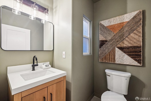 bathroom with toilet, vanity, and plenty of natural light