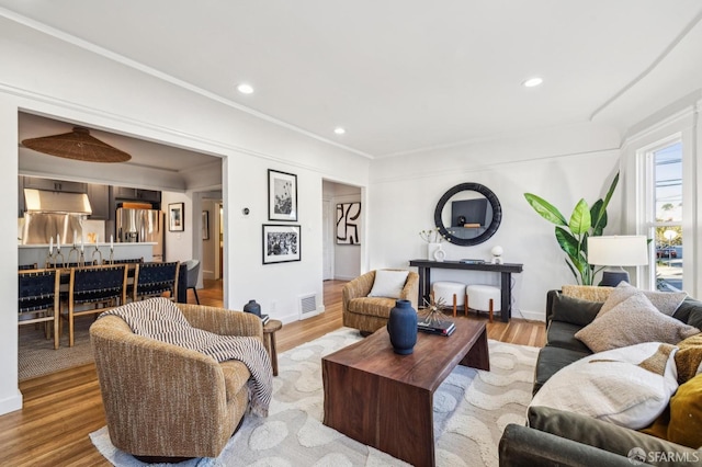 living room with light wood-type flooring and crown molding