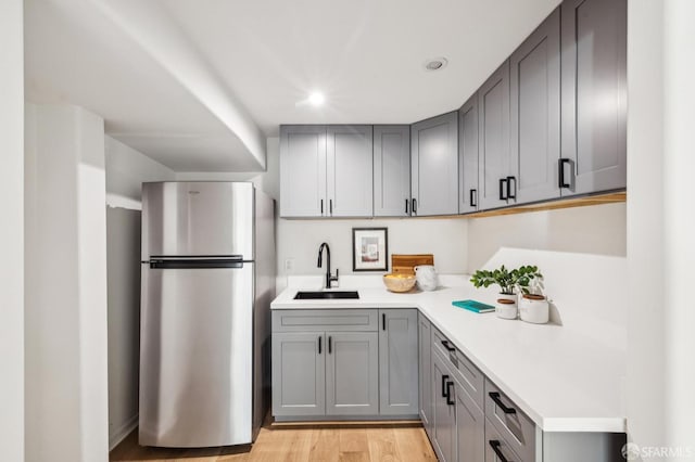 kitchen with stainless steel fridge, light hardwood / wood-style flooring, gray cabinetry, and sink