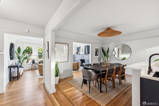 dining space featuring light hardwood / wood-style floors, a brick fireplace, and sink