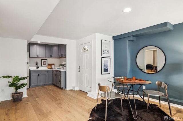 kitchen with white fridge, light hardwood / wood-style floors, gray cabinetry, and sink