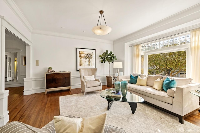 living room with crown molding, decorative columns, and wood finished floors