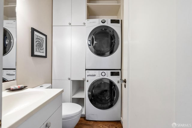 washroom with laundry area, a sink, dark wood finished floors, and stacked washing maching and dryer