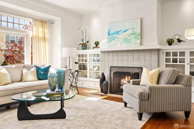 sitting room with ornamental molding, a tiled fireplace, and wood finished floors