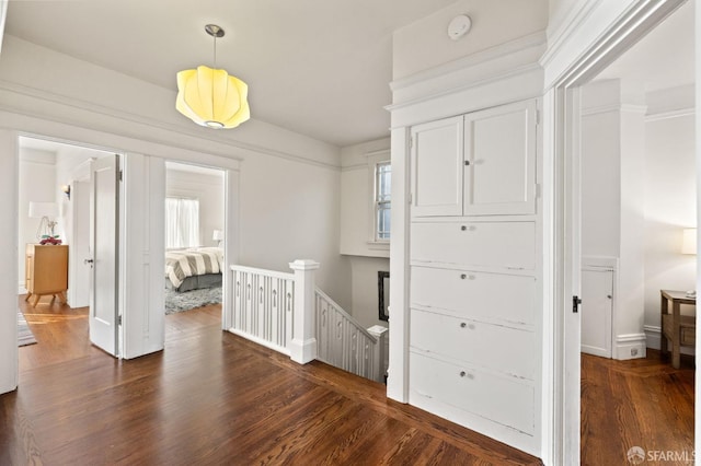 hall with dark wood finished floors, an upstairs landing, and baseboards