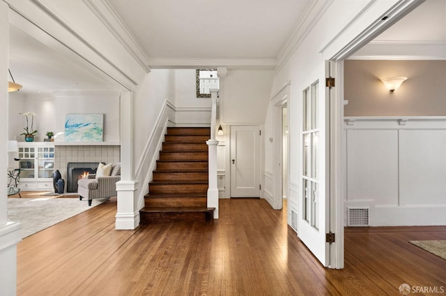 interior space with visible vents, a decorative wall, wood finished floors, and ornamental molding