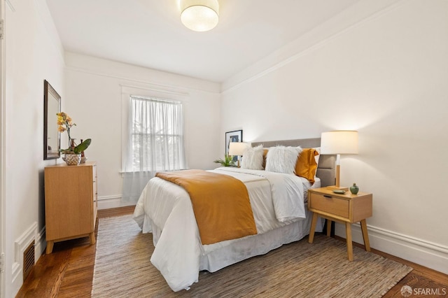 bedroom with visible vents, baseboards, and wood finished floors